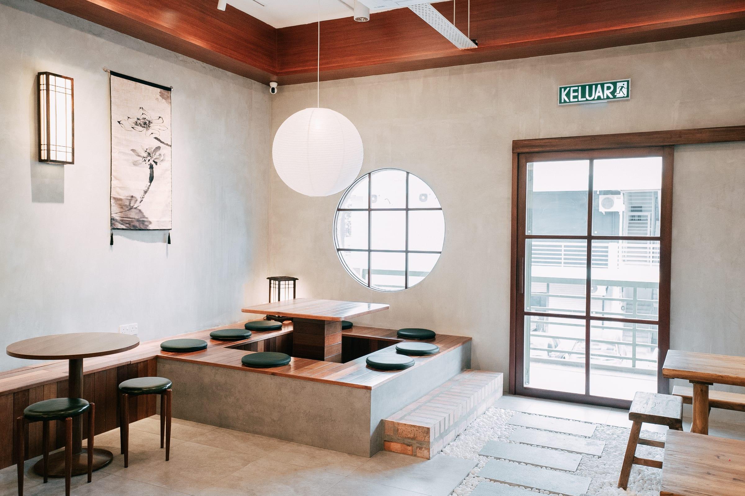 The café: paper lantern, round window, sunken seating and the door